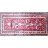 A North East Persian Zabul Belouch rug, repeating bird and petal motifs on a rouge field within