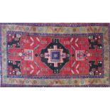 A Persian Sarouk carpet with central geometric medallion, surrounded by animal motifs on a red