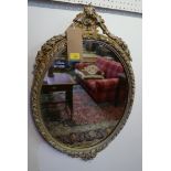 A gilt framed oval wall mirror with swag cresting. H.77cm