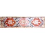A North West Persian Heriz runner, repeating stylised geometric motifs on a rouge field, guarded
