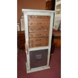 A collectors cabinet, with glass door and metal plate revealing six small drawers and storage space,