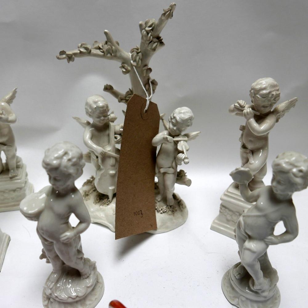 A collection of Capodimonte white glazed cherubs, each playing musical instruments, consisting of