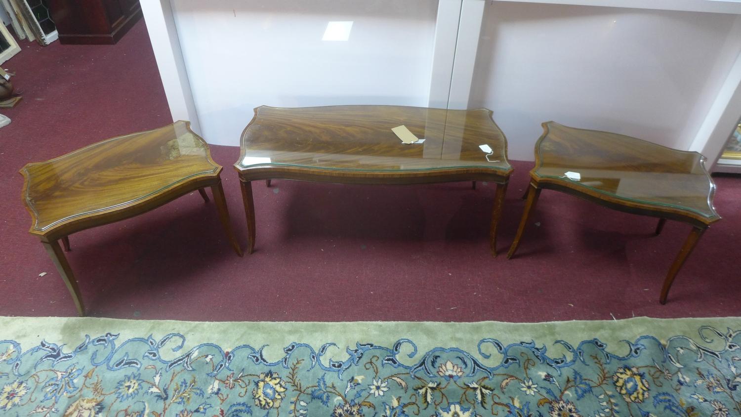 A 20th century mahogany serpentine coffee table with a pair of matching side tables