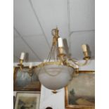 An early 20th century gilt metal six branch chandelier, with glass column, decorated with rams heads