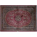 A Kashan style carpet with central floral medallion on a red ground, contained by floral borders,