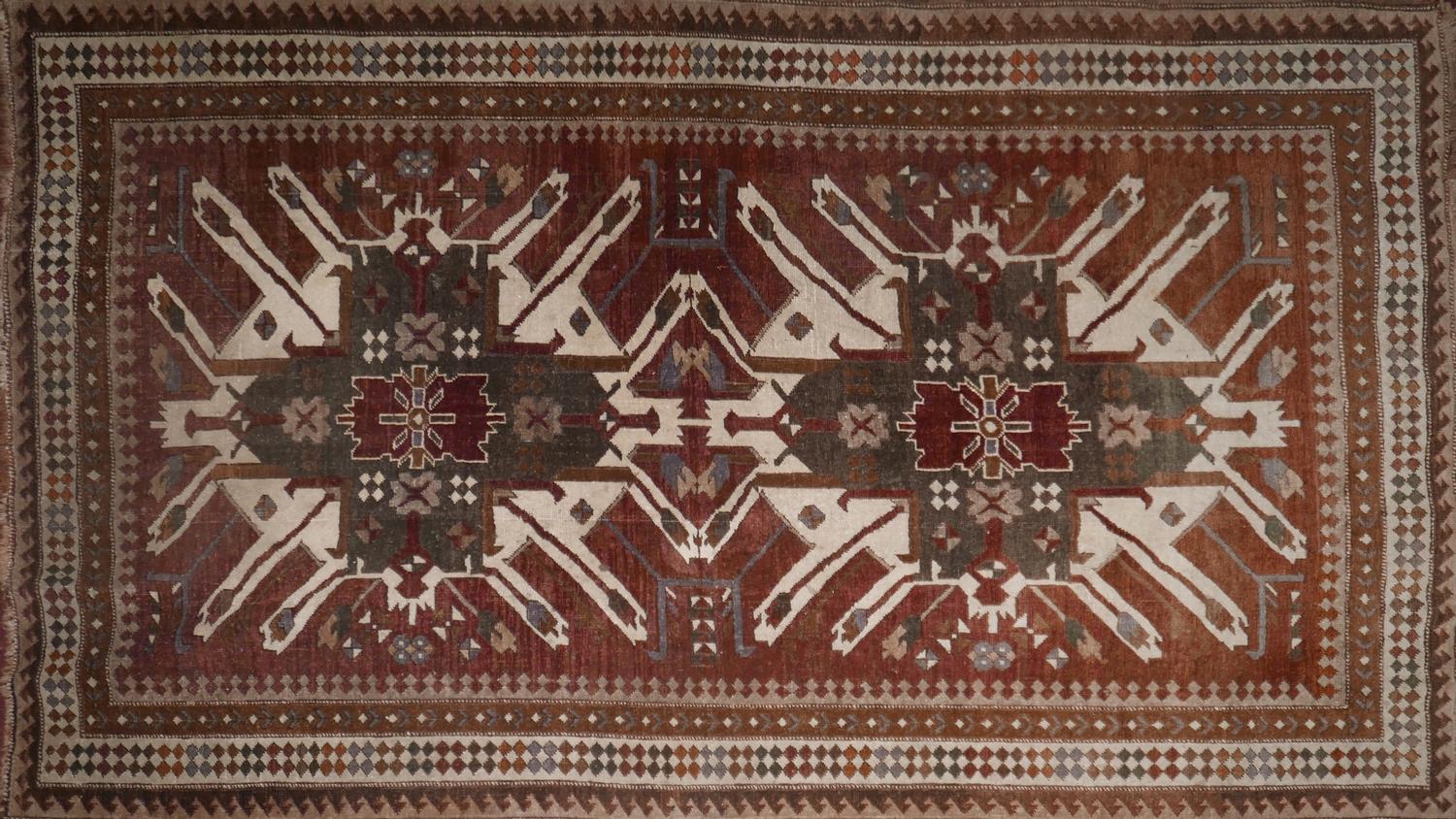 A 20th century north west Persian rug with two large geometric medallions, on a green and maroon