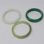 Three, polished green jade bangles in hues of dark green dia: 7cm, paler green dia: 6.8cm and