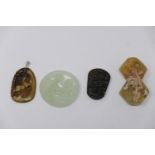 A collection of four Chinese carved jade pendants of various form and colour of jade, (one having