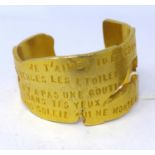 A Lancome, Paris, 'Poeme' large and weighty gilt metal cuff bracelet adorned with a French love