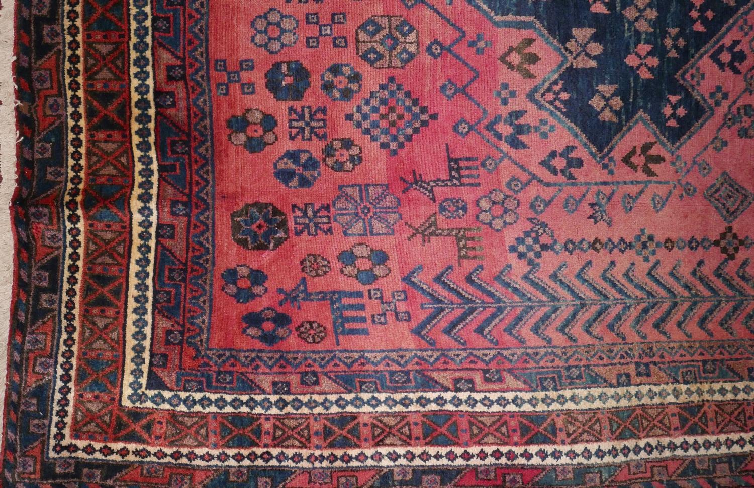 A North West Persian Kurdish carpet, triple eagle motifs on a pale rouge field, within stylised - Image 2 of 3