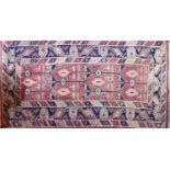 A hand-made Persian red ground rug, geometric motifs on red ground, within geometric border on a