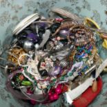 A large circular box containing a variety of costume jewellery to include earrings, necklaces,