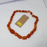 A large, baltic natural amber bead necklace composed of twenty-five, graduated beads of polished,
