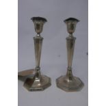 A pair of filled silver candlesticks, raised on octagonal base, by Harrison Brothers & Howson (
