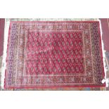 A Bokhara style rug with repeating elephant pad motifs, on a red ground, contained by geometric