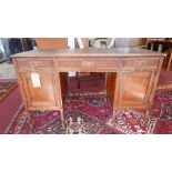An Arts & Crafts mahogany desk, with three drawers above two cupboard doors, raised on turned legs