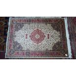 A Kashan style carpet with central floral medallion, on a beige ground, contained by floral borders,