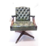 A 20th century mahogany desk chair, with green leather button back upholstery, raised on castors