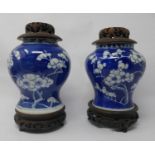 A pair of 19th century Chinese blue & white porcelain vases with hardwood stands and covers, H.20cm