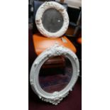 An ornate white moulded oval wall mirror H.93 W.63cm and a smaller round similar