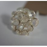 A sterling silver and moonstone cluster ring composed of fourteen, oval moonstone cabochons in