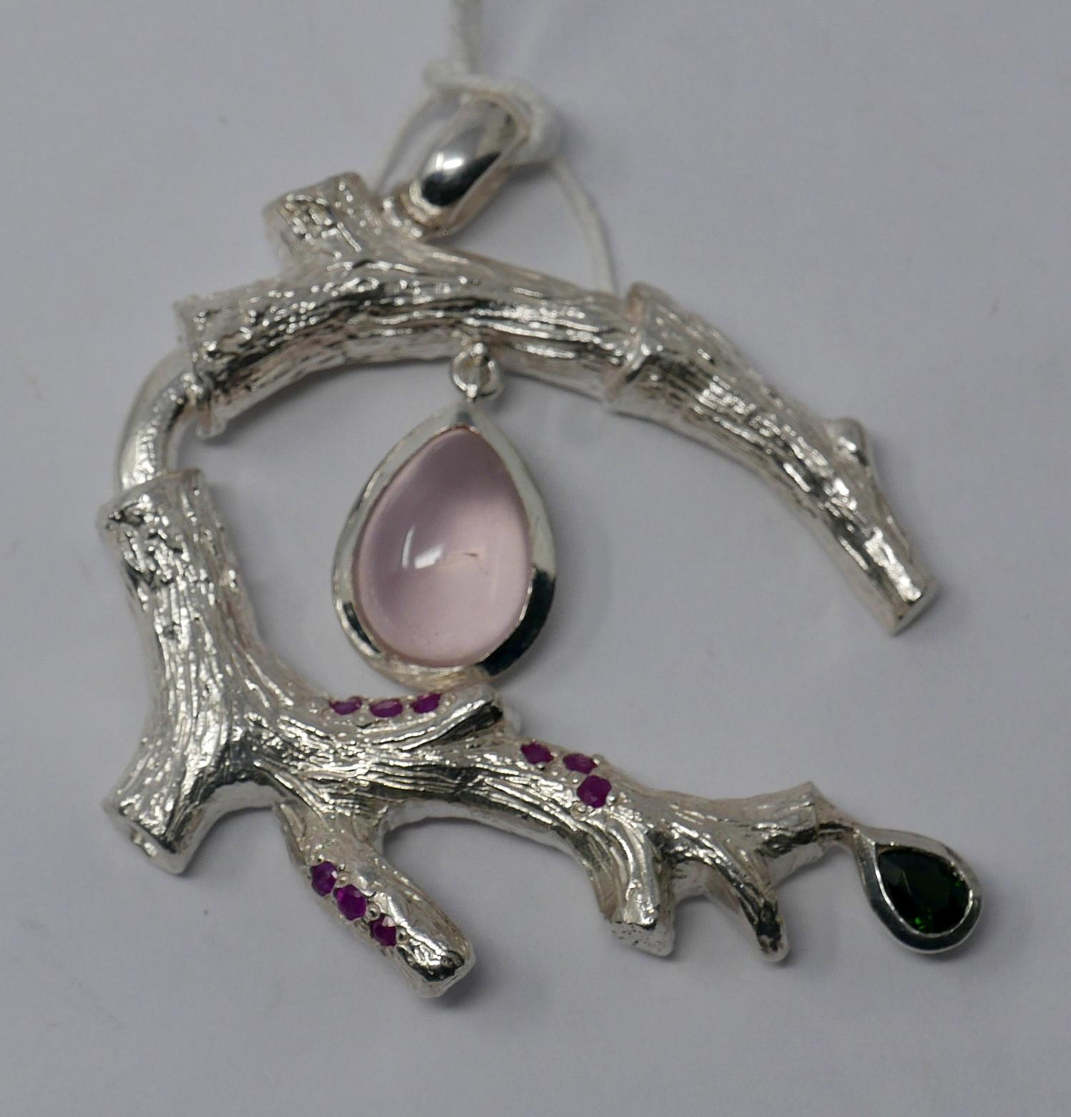 A sterling silver pendant in the form of a branch studded with nine rubies and suspended by a rose