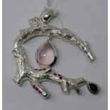 A sterling silver pendant in the form of a branch studded with nine rubies and suspended by a rose