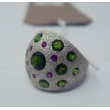 A sterling silver bombe ring inset with six rubies and thirteen green garnets to a textured