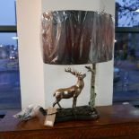 A contemporary lamp modelled as a stag by a tree, with oval shade, H.65 L.35cm