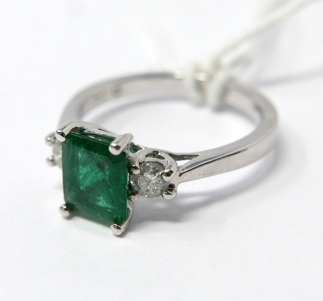 An 18ct white gold, emerald and double diamond ring, centrally set with a stepped-cut,