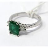 An 18ct white gold, emerald and double diamond ring, centrally set with a stepped-cut,