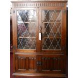 A Jacobean style oak bookcase with leaded glazed doors on bracket feet. H.136 W.96 D.30cm