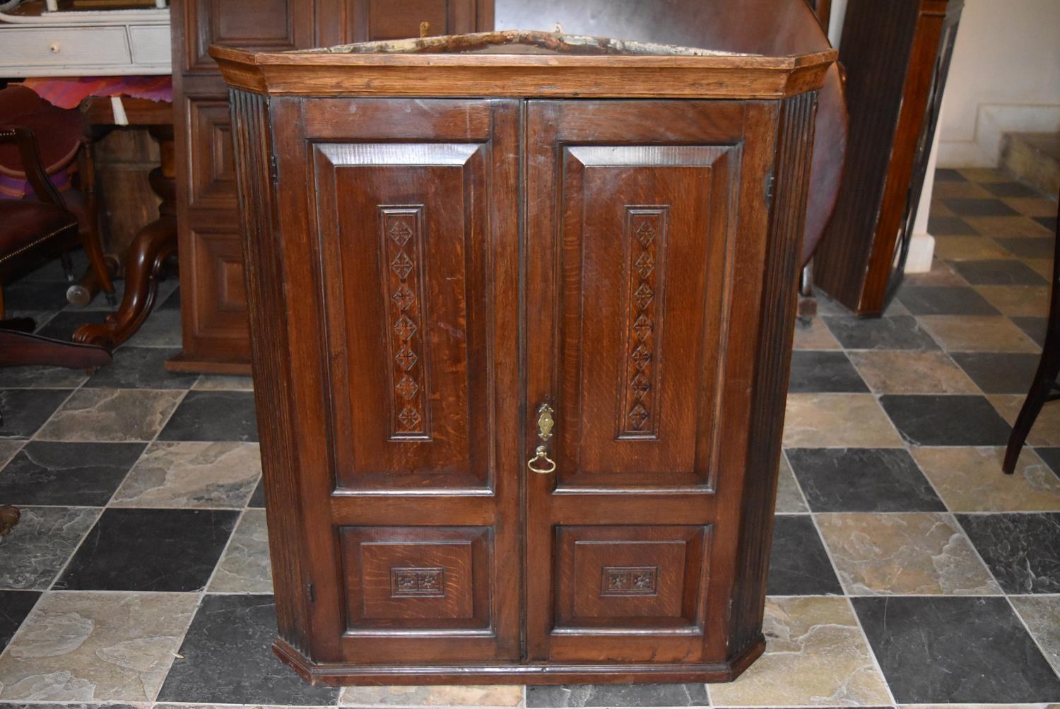 A Georgian oak hanging corner cupboard fitted panel doors and shelved interior. H = 104cm W = 89cm D