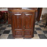 A Georgian oak hanging corner cupboard fitted panel doors and shelved interior. H = 104cm W = 89cm D