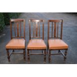 Three early 20th century oak dining chairs in tan leather upholstery, H = 101cm W = 46cm D = 43cm