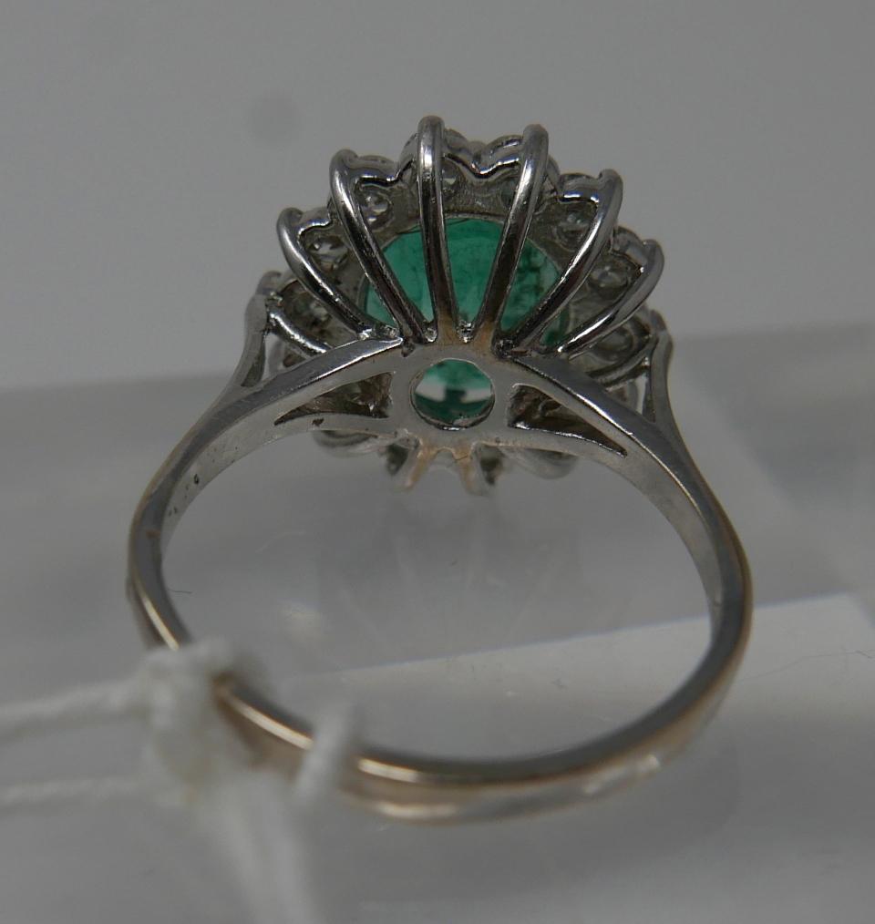 An 18ct white gold, emerald and diamond cluster ring, centrally set with a large, oval faceted - Image 4 of 6