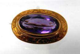 An 18ct yellow gold, Victorian, oval amethyst brooch with engraved scroll border, 1.7 x 2.5cm, 5.2g.