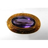 An 18ct yellow gold, Victorian, oval amethyst brooch with engraved scroll border, 1.7 x 2.5cm, 5.2g.