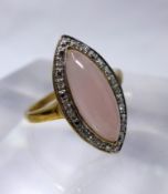 A 9ct yellow gold diamond and rose quartz ring, centrally set with a marquise-shaped rose quartz