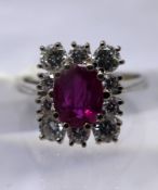 An 18ct white gold, natural ruby and diamond cluster ring, the central oval faceted natural ruby