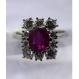 An 18ct white gold, natural ruby and diamond cluster ring, the central oval faceted natural ruby