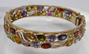 A yellow gold bangle studded with gemstones and rose gold accents, Dia: 6.5cm, 29g. (-sapphire,