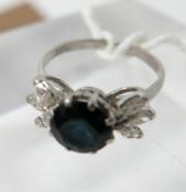 An 18ct white gold, sapphire and diamond ring, the round, faceted sapphire in 8-claw mount flanked