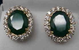 A boxed pair of 18ct yellow gold, emerald and diamond cluster stud earrings, each earring composed