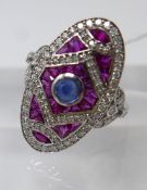 An 18ct white gold, Art Deco style diamond ruby and sapphire ring, composed of an oval-shaped