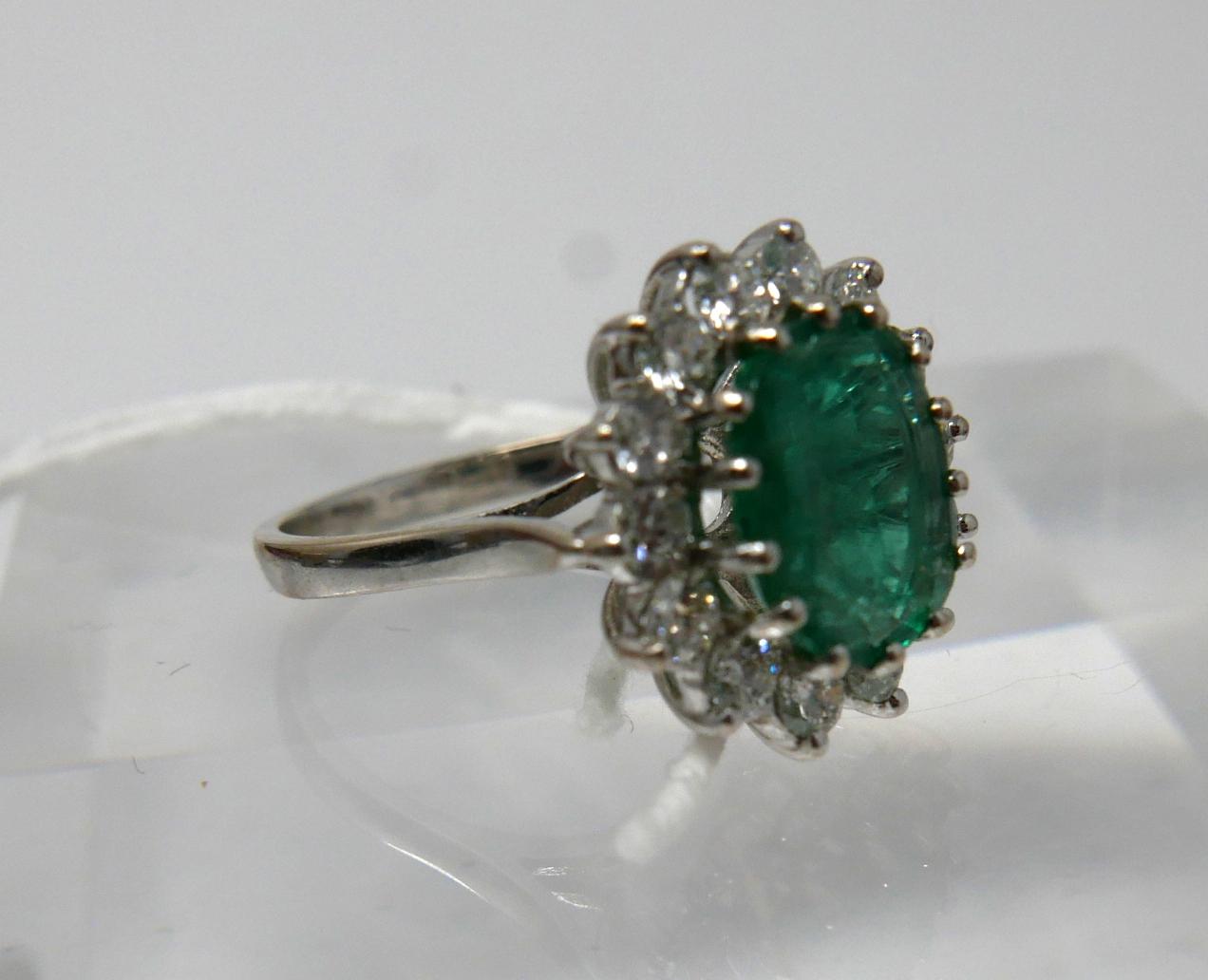 An 18ct white gold, emerald and diamond cluster ring, centrally set with a large, oval faceted - Image 3 of 6