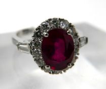 An 18ct white gold, ruby and diamond cluster ring, centrally set with an oval faceted ruby