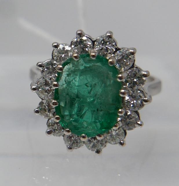 An 18ct white gold, emerald and diamond cluster ring, centrally set with a large, oval faceted - Image 5 of 6