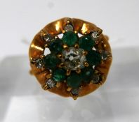 An 18ct yellow gold, diamond and emerald cluster ring, centrally set with a round brilliant cut