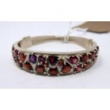 A sterling silver bangle in set with 27 faceted natural garnets of various size and cut, Dia: 7cm,